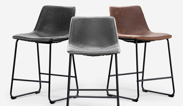 Set on a white background is a collection of faux leather bar stools in three different colours which is ebony, grey and brown with black metal support legs